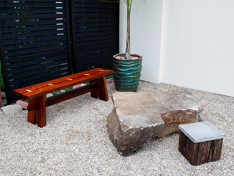 Mahogany split top bench held together with traditional joinery, including Hard Maple and Purple Heart bowtie inlays holding the top together, outdoor natural view.