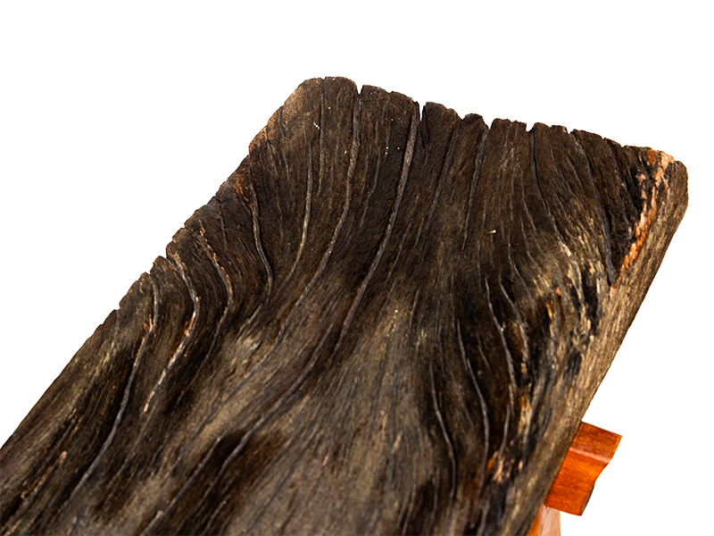 Weathered mahogany waterfall bench with sculpted split leg and purple heart accents. Top board closeup.